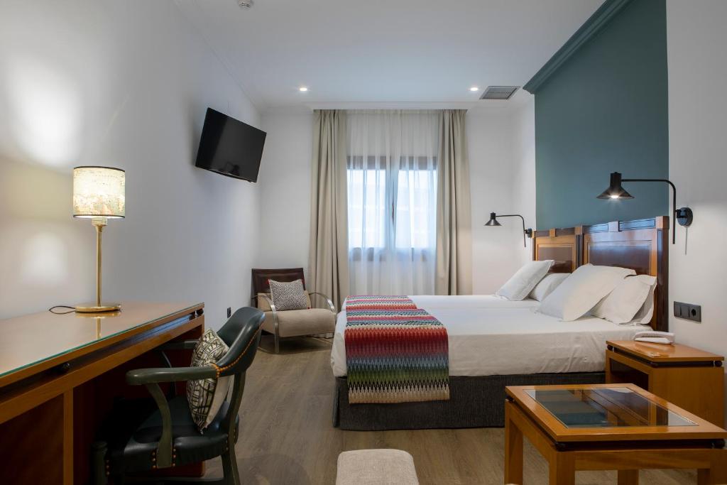 una habitación de hotel con una cama y un escritorio en Hotel Don Curro, en Málaga