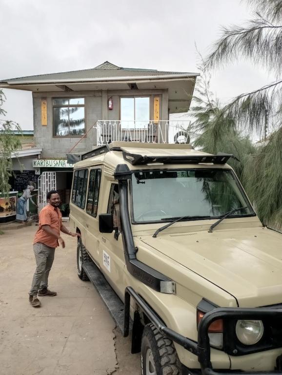 a man standing next to a jeep parked in front of a house at The Greenhouse Hostel Arusha Tanzania in Arusha