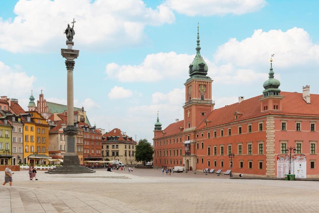 a city square with a statue in front of buildings at Apartament przy Placu Zamkowym by Renters in Warsaw