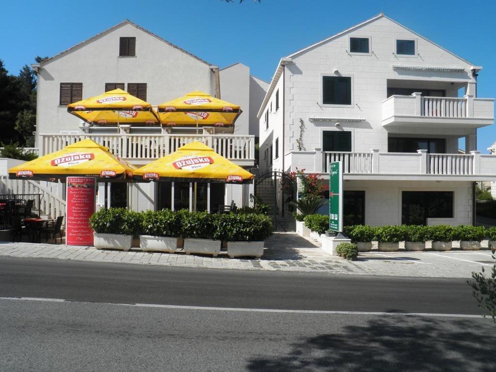 a restaurant with yellow umbrellas in front of a building at Apartments Logos in Cavtat