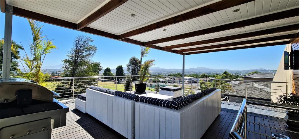 Un balcón con muebles blancos y vistas. en Walters Lane Luxury Accommodation main house - No loadshedding, en Ciudad del Cabo