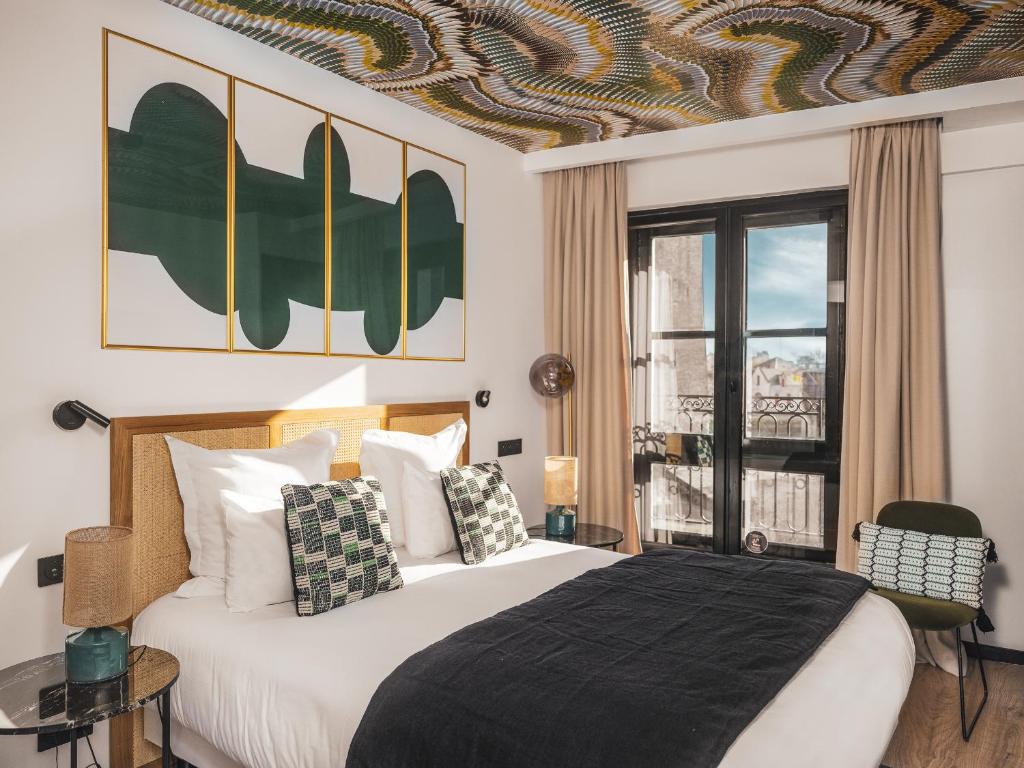 Un dormitorio con una cama grande y una ventana. en Maisons du Monde Hôtel &amp; Suites - La Rochelle Vieux Port, en La Rochelle