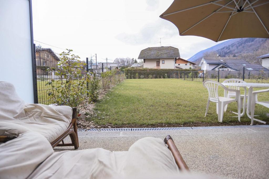 eine Terrasse mit einem Tisch, Stühlen und einem Sonnenschirm in der Unterkunft Le Jardin de Boubioz in Sévrier