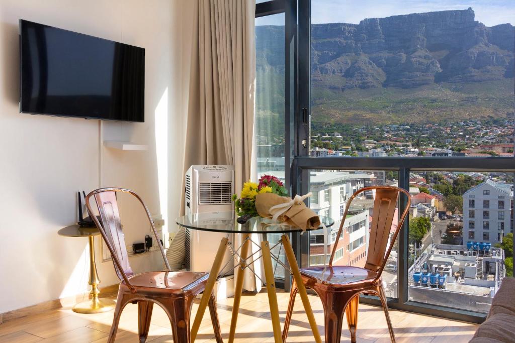 ein Wohnzimmer mit einem Tisch und Stühlen sowie Aussicht in der Unterkunft Urban Oasis At The Four Seasons in Kapstadt