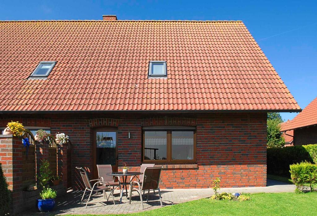 een stenen huis met een tafel en stoelen bij Ferienwohnungen Haus Meeresleuchten in Bensersiel