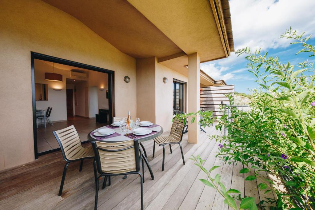 a patio with a table and chairs on a deck at Résidence Les Terrasses de Rondinara in Bonifacio
