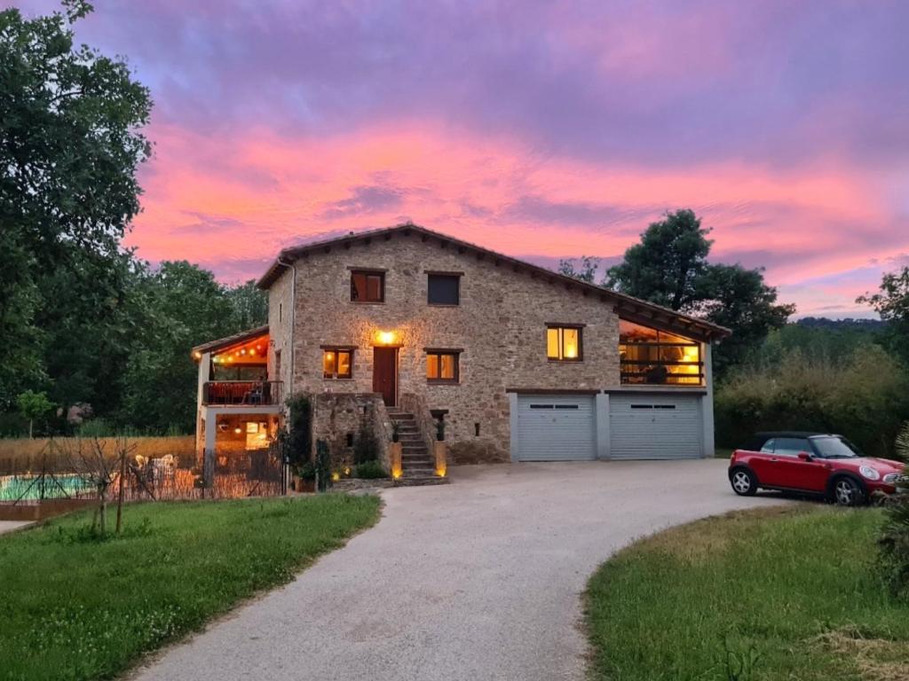 a red car parked in front of a stone barn at Harveys Homestay - Adults only in Mieres