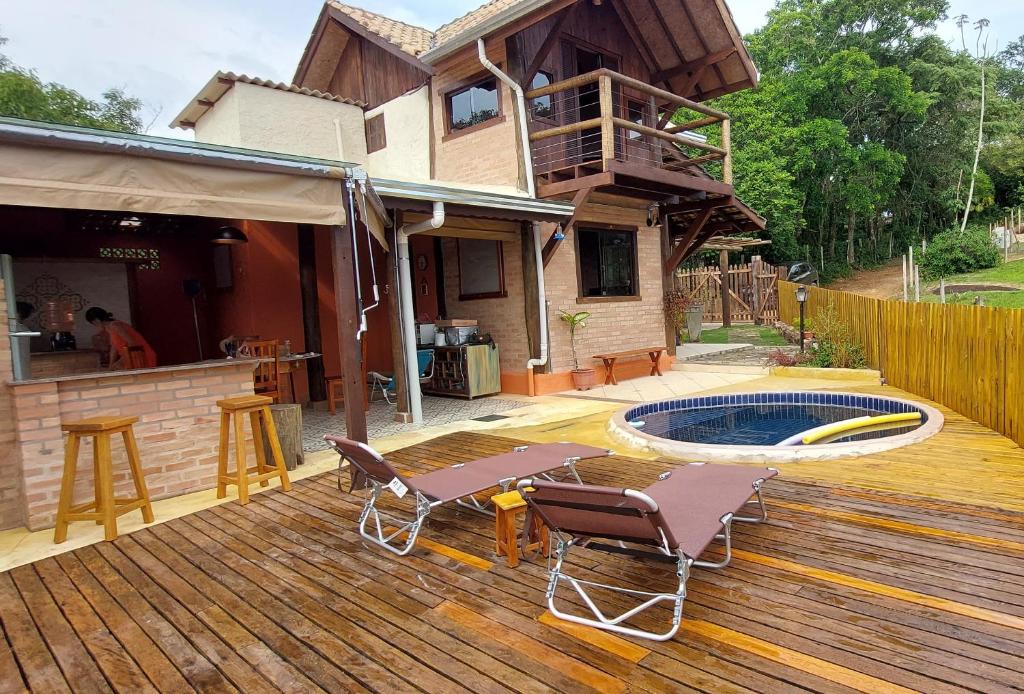 a deck with a table and chairs and a swimming pool at Chalé da Serra in Bragança Paulista