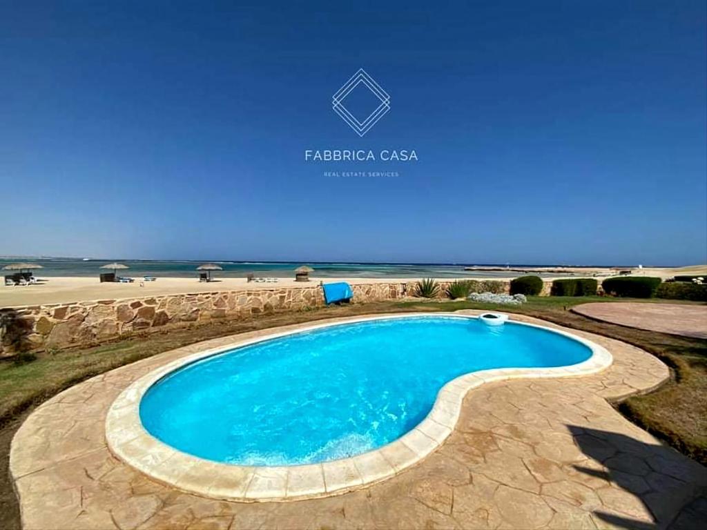 una piscina con spiaggia sullo sfondo di FabbricaCasa Sea Front Villa, Oriental Coast a Marsa Alam
