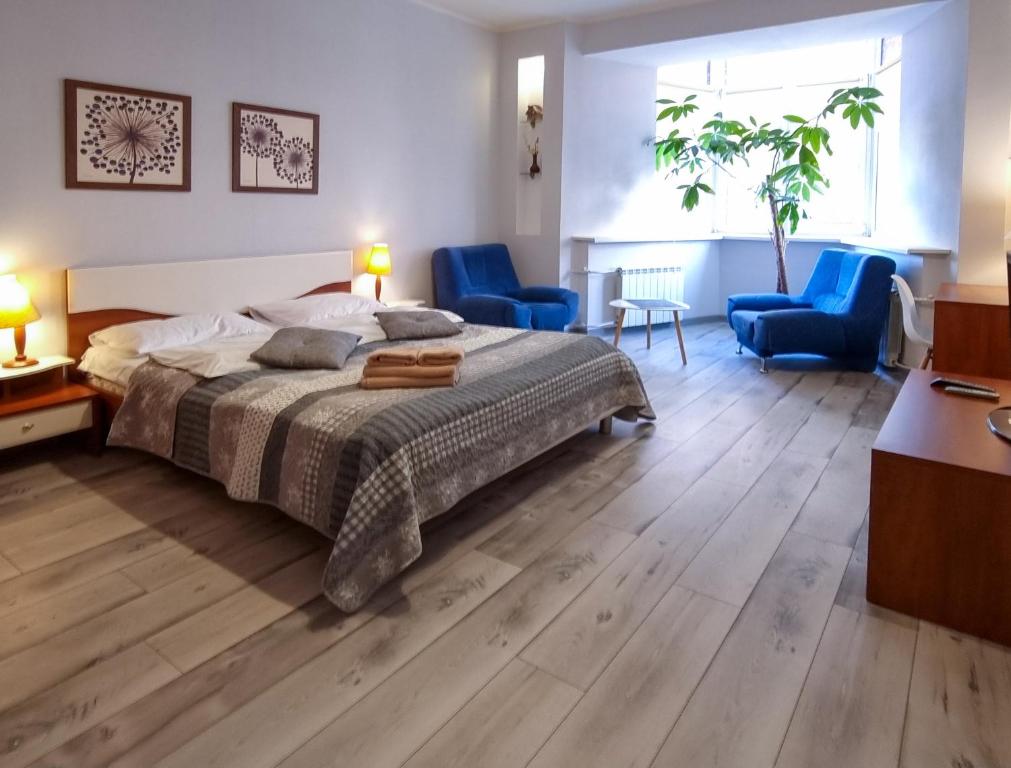 um quarto com uma cama e duas cadeiras azuis em Home Hotel Apartments on Kontraktova Ploshcha em Kiev