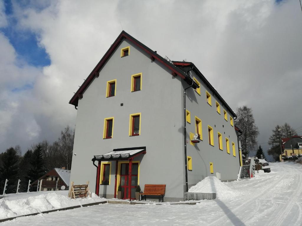 a large white building with yellow windows in the snow at Apartmany Troll in Bublava