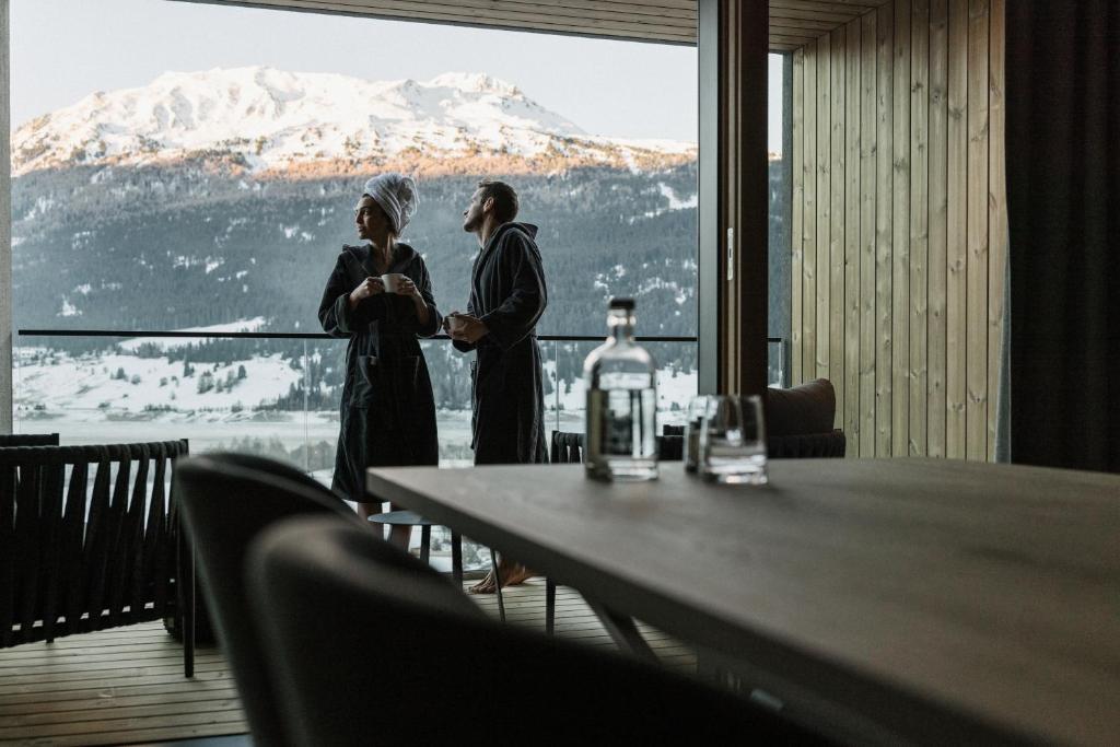 two women standing in front of a table with a view at Lacumontes Lake View Apartments in Curon Venosta
