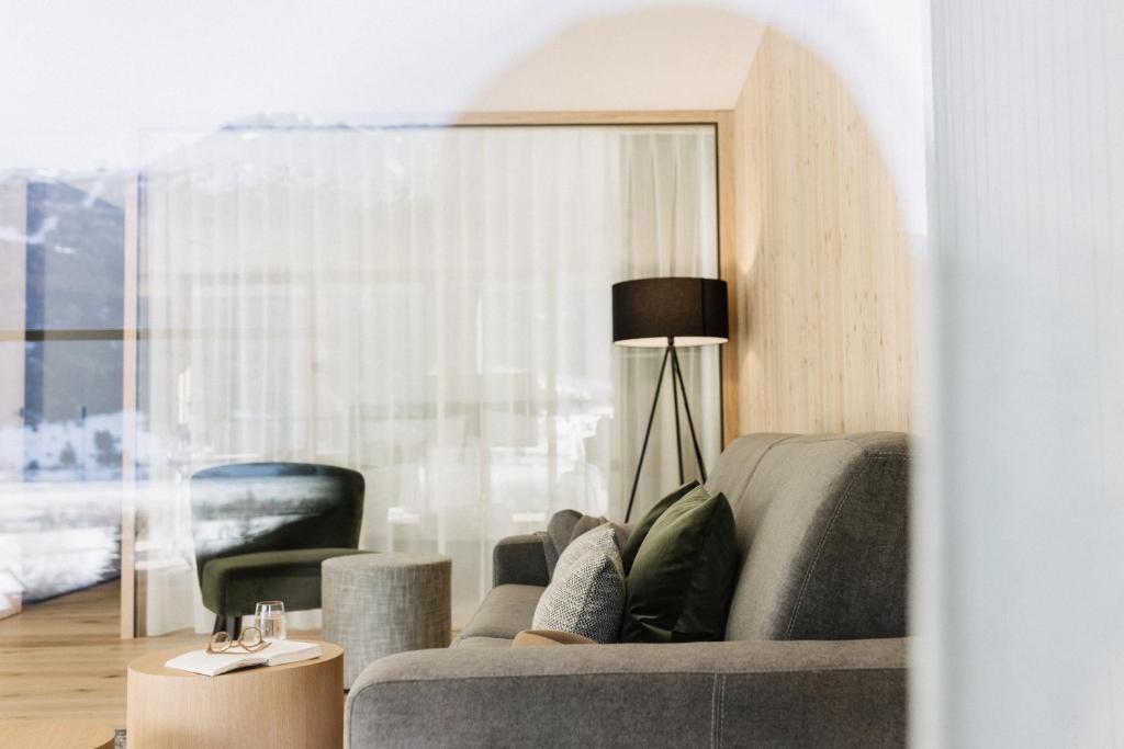 ein Wohnzimmer mit einem grauen Sofa und einem Stuhl in der Unterkunft Lacumontes Lake View Apartments in Graun im Vinschgau