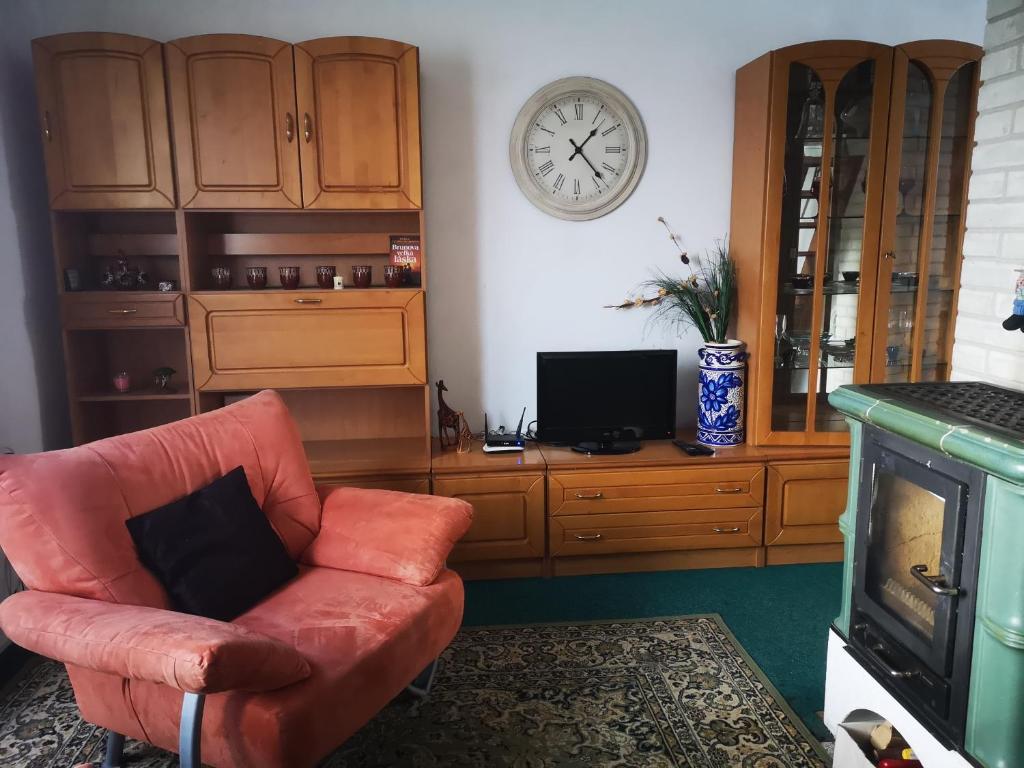 a living room with a chair and a clock on the wall at Ubytovanie v sukromi in Dolní Bzince