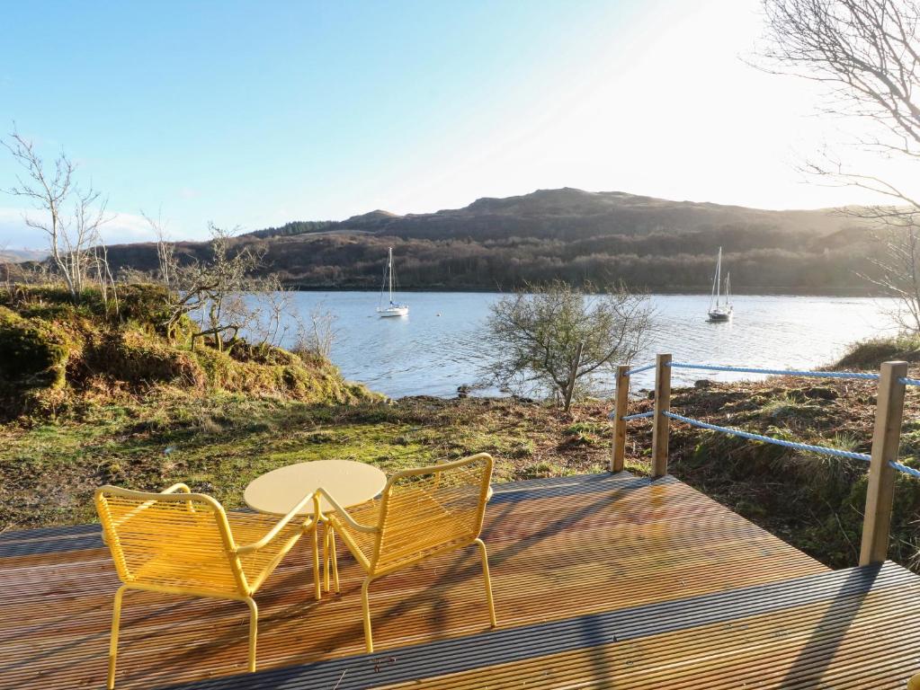 una mesa y 2 sillas en una terraza con vistas al agua en Kelpie, en Lochgilphead