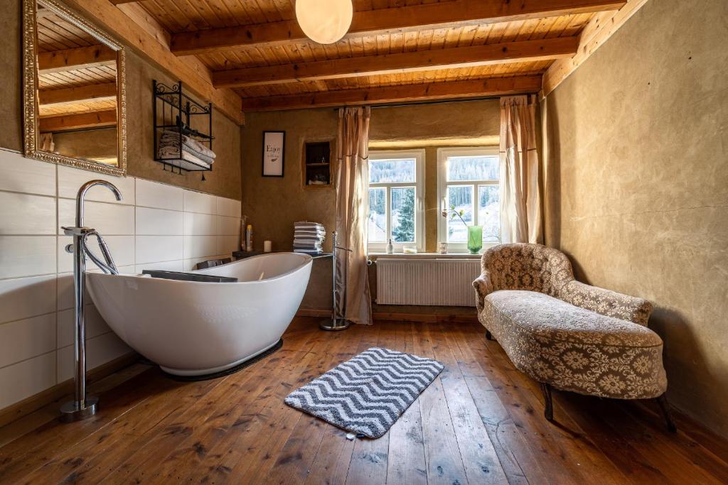 a bathroom with a tub and a chair and a window at Historisches Ferienhaus "Zur Linde" in Hausten