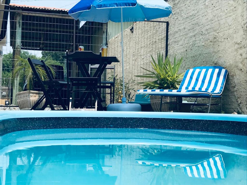 uma piscina com um guarda-sol, uma mesa e cadeiras em Cantinho Dom Inácio em São Gabriel