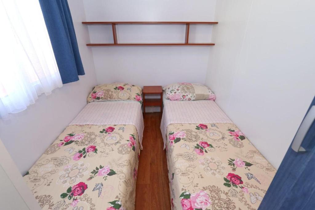 two twin beds in a small room with a window at Poolside Mobile Home in Turanj