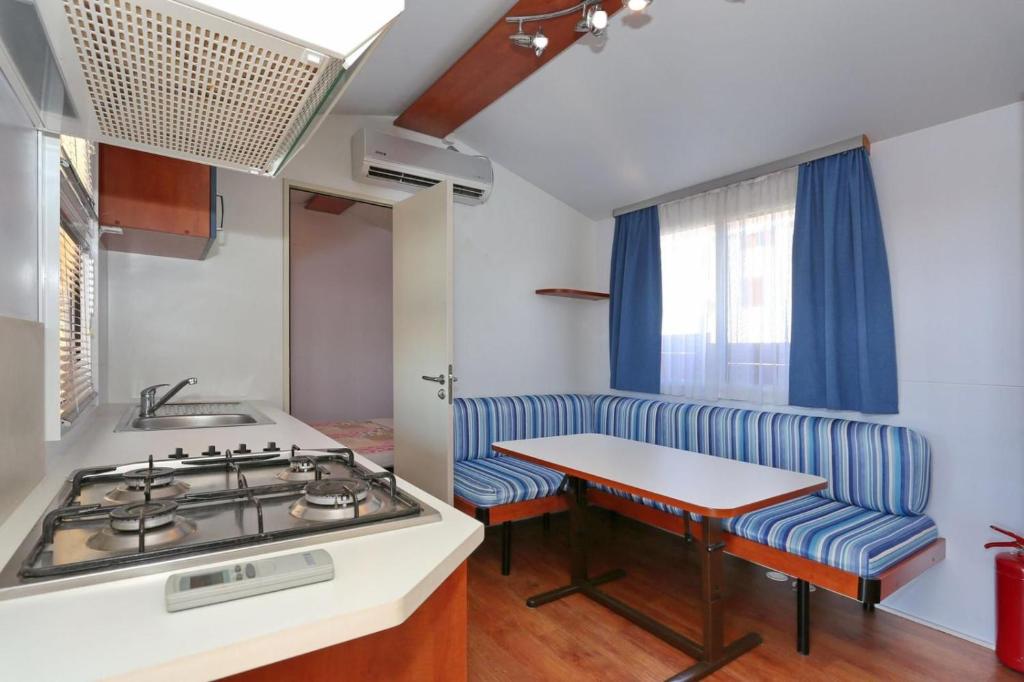 a kitchen with a stove and a sink and a table at Poolside Mobile Home in Turanj
