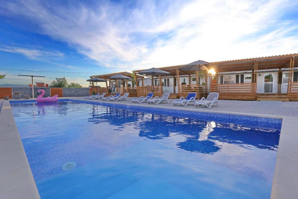 una piscina con sillas y una casa en Poolside Mobile Home en Turanj