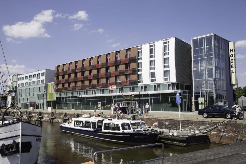 a boat in the water in front of a building at Nordsee Hotel Fischereihafen in Bremerhaven