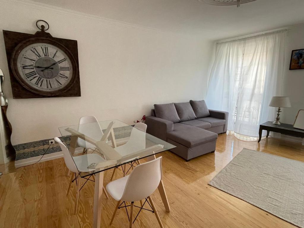 a living room with a glass table and a clock on the wall at Beautiful apartment downtown Lisbon in Lisbon