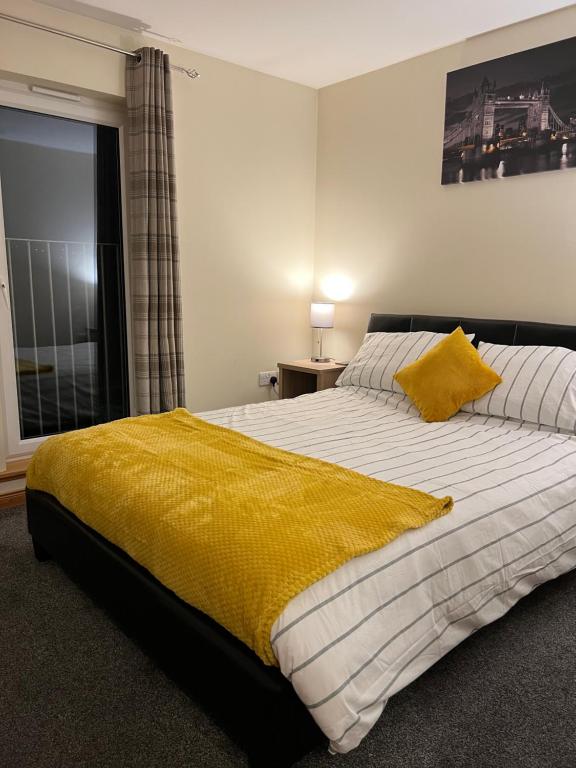 a bedroom with a large bed with a yellow blanket at Bright and modern 2 bedroom home in Kirkwall in Kirkwall