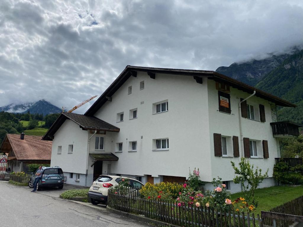 una casa bianca con macchine parcheggiate di fronte di Spring Inn Apartments a Meiringen