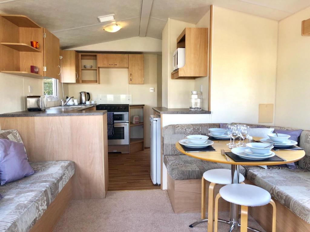 a small kitchen with a table and a couch at Sycamore Caravan in Mullion