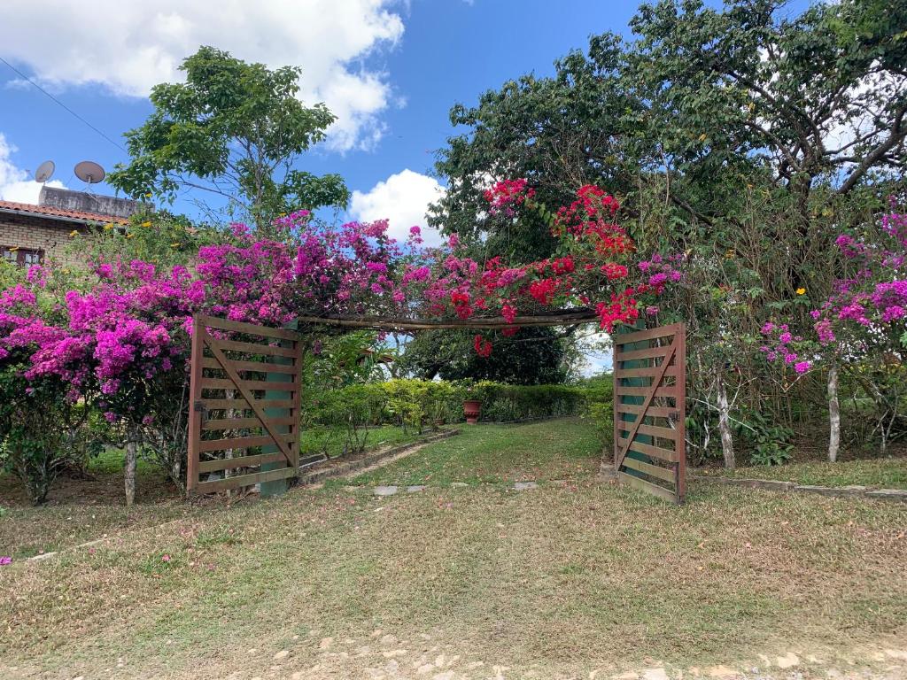 einen Garten mit rosa Blumen auf einem Holztor in der Unterkunft Sítio São Gerardo - Aconchegante casa no campo. in Guaramiranga