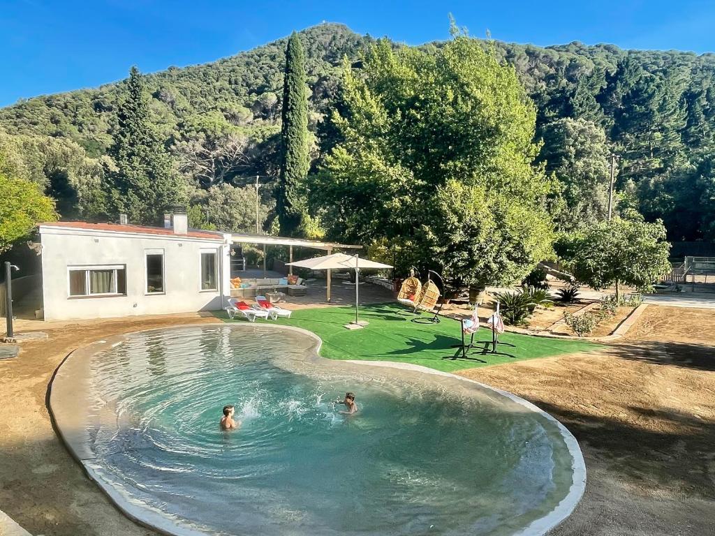 two people swimming in a swimming pool in a backyard at CASA RURAL EL JARDI con Piscina, Jardin y Barbacoa in Arenys de Munt