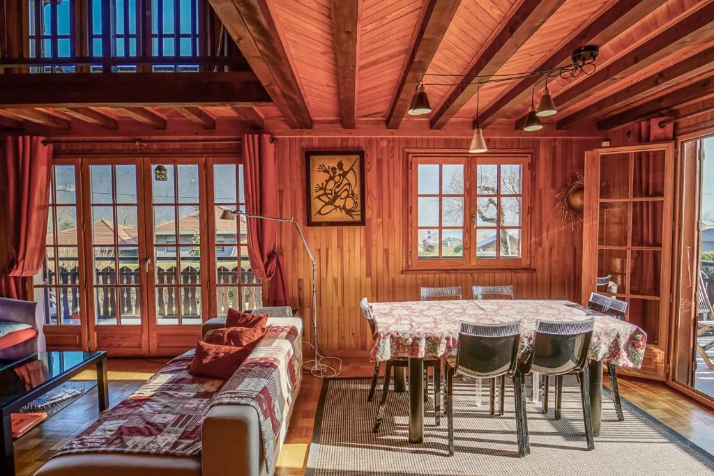 ein Esszimmer mit einem Tisch, Stühlen und Fenstern in der Unterkunft Le Chalet Soleil in Lathuile