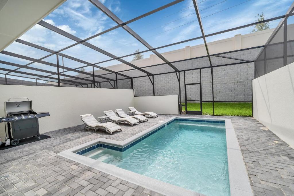 a swimming pool with a glass roof with chairs and a grill at Free Waterpark Private Splash Pool Near Disney in Davenport
