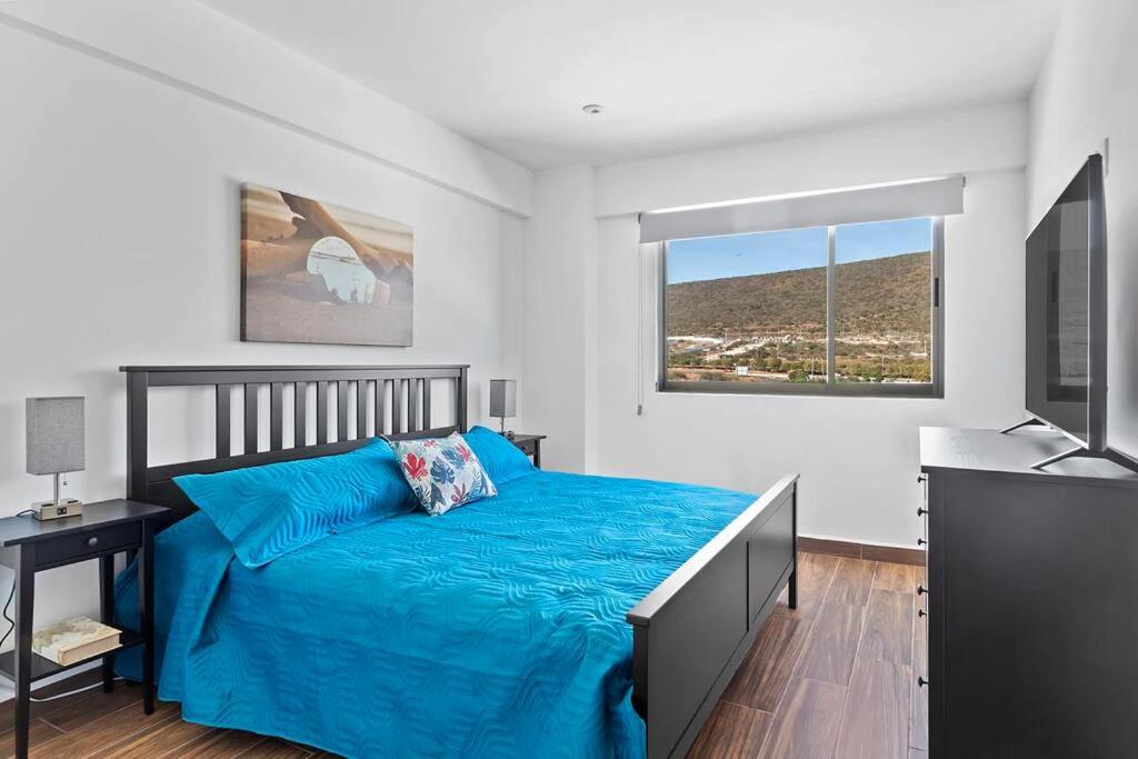 um quarto com uma cama azul e uma televisão em +MS +Departamento Nuevo +Inmejorable Vista +Amenities Vitea 1004 em Querétaro