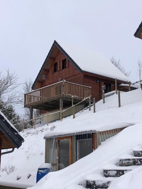 une maison recouverte de neige devant dans l'établissement Chalet montagnard Perce Neige avec terrasse plein sud-5 personnes, à Murat-le-Quaire