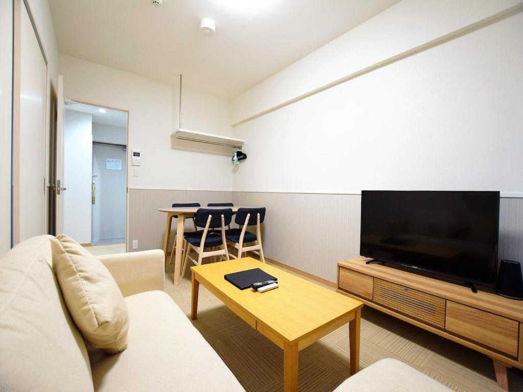 sala de estar con sofá, TV y mesa en Land-Residential Hotel Fukuoka - Vacation STAY 81846v, en Fukuoka