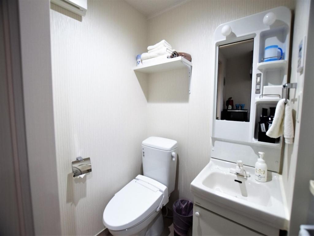 La salle de bains blanche est pourvue de toilettes et d'un lavabo. dans l'établissement Land-Residential Hotel Fukuoka - Vacation STAY 81843v, à Fukuoka