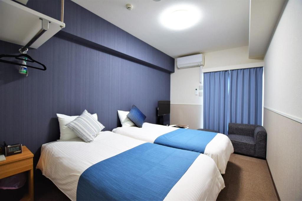 una camera d'albergo con due letti e una parete blu di Land-Residential Hotel Fukuoka - Vacation STAY 81831v a Fukuoka