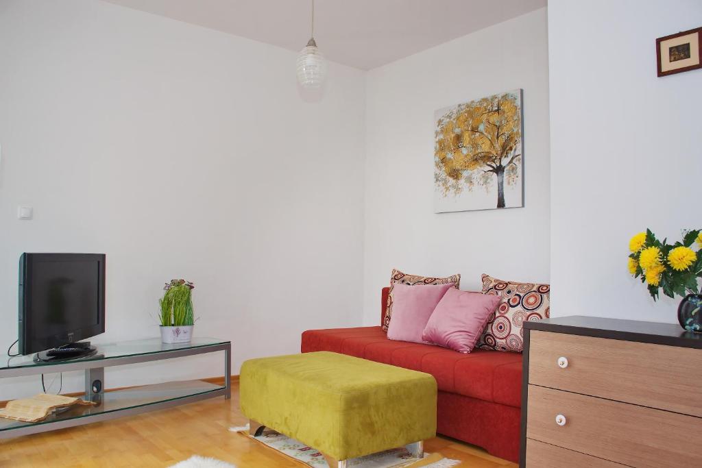 a living room with a red couch and a tv at SunShine in Novalja