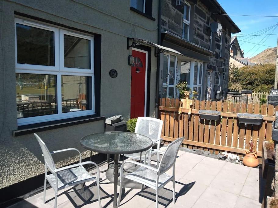 eine Terrasse mit einem Tisch und Stühlen vor einem Haus in der Unterkunft Daisys cottage. Blaenau ffestiniog. in Blaenau-Ffestiniog