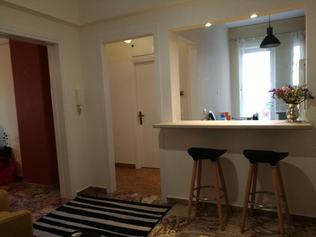 una cucina con bancone e 2 sgabelli da bar di Maria's Cozy apartment in Palaio Faliro ad Atene