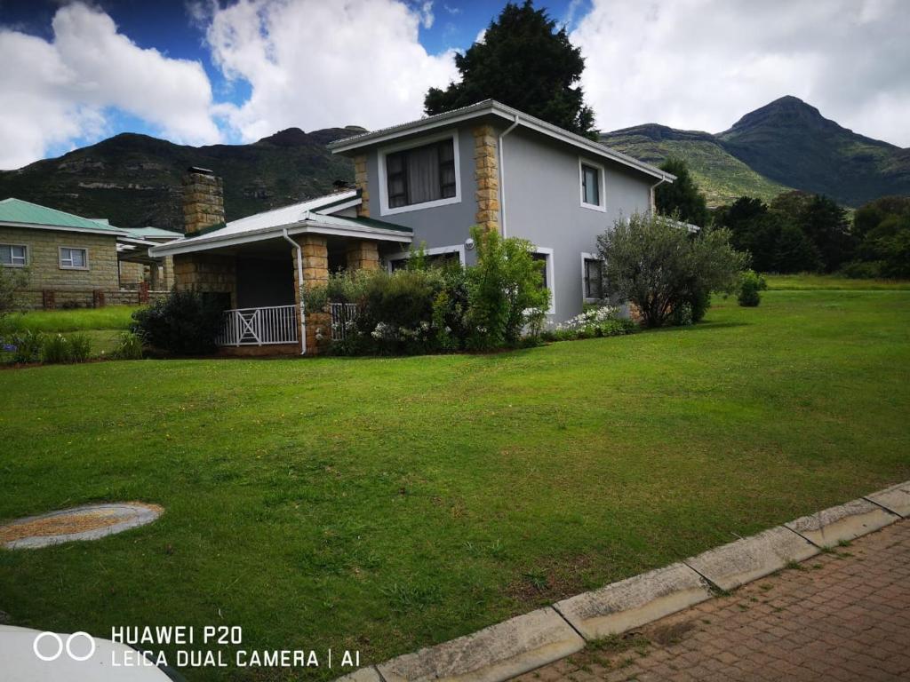 a white house with a lawn in front of it at Villa Mohau 178 in Clarens