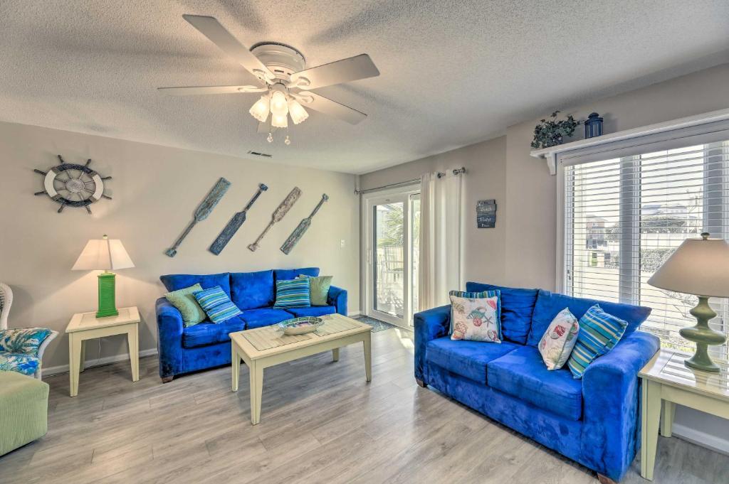 a living room with blue couches and a ceiling fan at Emerald Isle Condo with Indoor Pool and Beach Access! in Emerald Isle