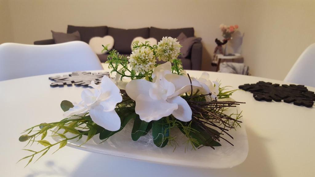 a white flower arrangement on a white plate on a table at Erholung Pur bei Nina in Bad Lauterberg