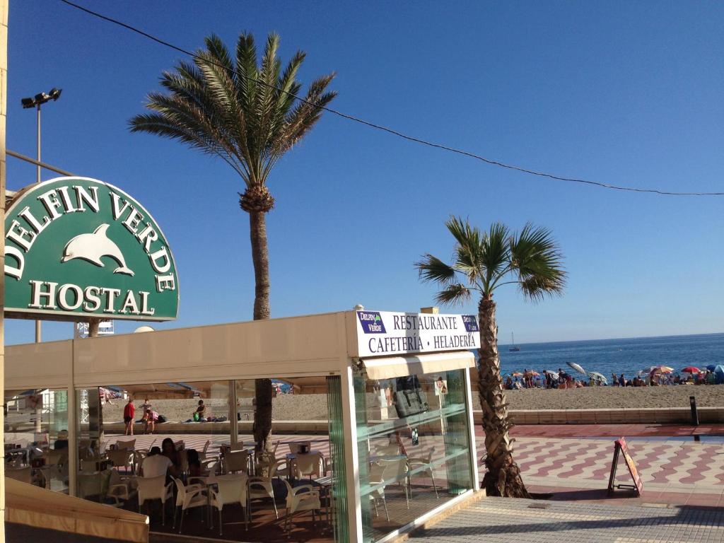 um sinal para um hotel com palmeiras e a praia em Hostal Delfin Verde em Almeria