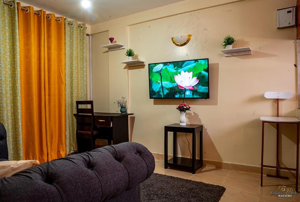 a living room with a couch and a flat screen tv at STYLISH 1BR APARTMENT IN KISUMU: FAST WI-FI, NETFLIX, SECURE PARKING in Kisumu