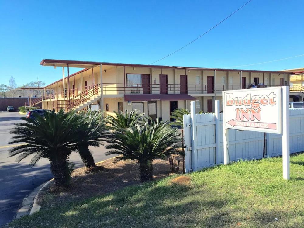 un edificio con un cartel y palmeras delante de él en Budget Inn, en Tallahassee