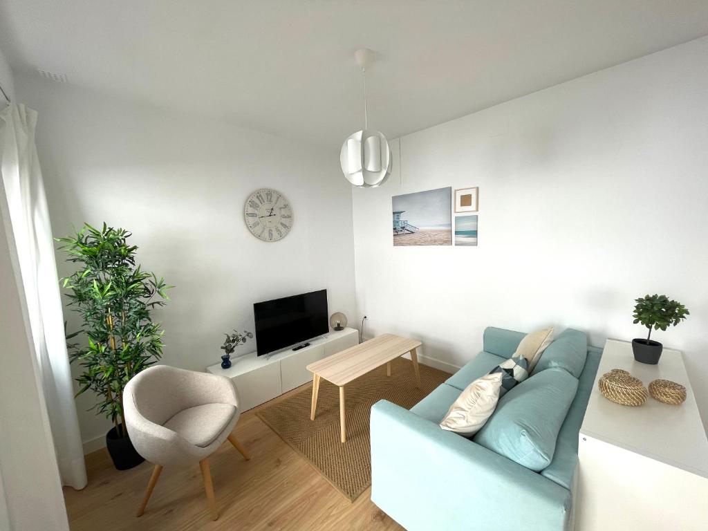uma sala de estar com um sofá azul e uma televisão em No 10 Cádiz em Cádiz