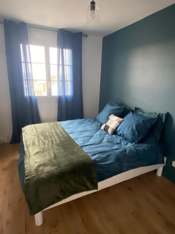 une chambre avec un lit avec des draps bleus et une fenêtre dans l'établissement Au bonheur des Damiettes, à Montluçon