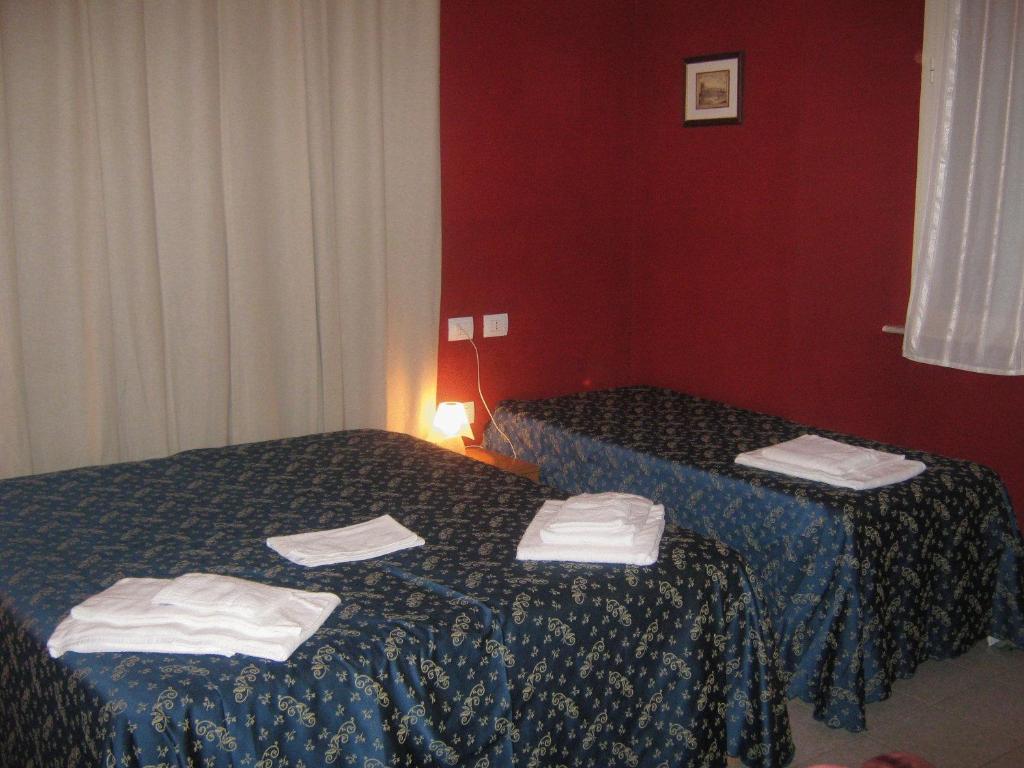 two beds in a red room with towels on them at Hotel Ferraro in Rome